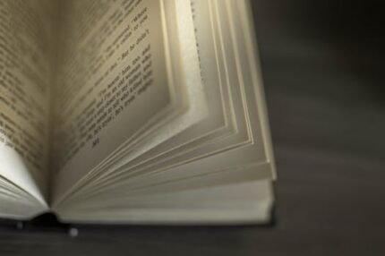 A close-up image of an open book with visible text, showcasing turning pages.